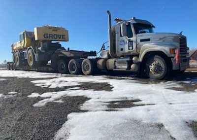 Alpha Milling heavy haul trucking service carrying large road maintenance equipment.